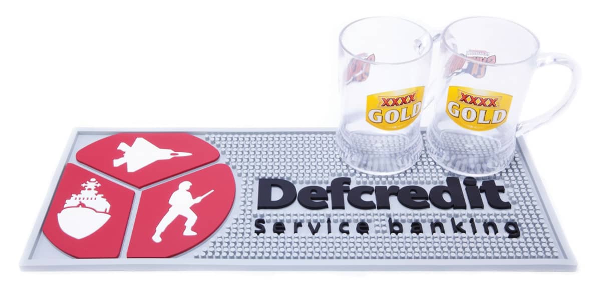 Two XXXX Gold beer mugs on a Defcredit service banking mat with military icons.