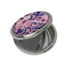 Round compact mirror with a pink and blue floral design on the lid, slightly open.