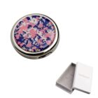 Round compact mirror with a pink and blue floral pattern, next to a white gift box.