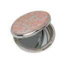 Round compact mirror with a pink floral design on the lid, partially open to show the mirror.