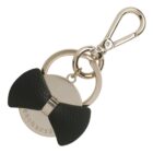 Gold keychain with a black bow and engraved Cacharel on a round metal tag.