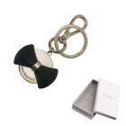 Gold keychain with a black bow and branded tag, shown with an open white gift box.