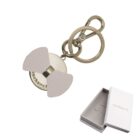 Gold keychain with a round charm and bow, next to an open white Cacharel gift box.