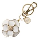 Gold keychain with a white flower and a round charm engraved with Coach New York.