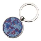 Silver keychain with a round charm featuring a blue and purple floral pattern.