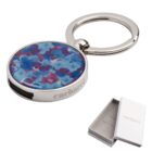 Round floral keychain with blue and purple flowers, silver rim, and a branded gift box.