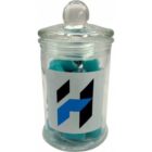 A glass jar with a lid, filled with blue candies, featuring a black and blue H label.