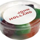 Small plastic container with colorful candy and a lid labeled JOHN HOLLAND in red text.
