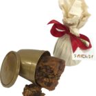 A brown plastic cup with cookie pieces spilled out, next to a wrapped gift with a red ribbon.