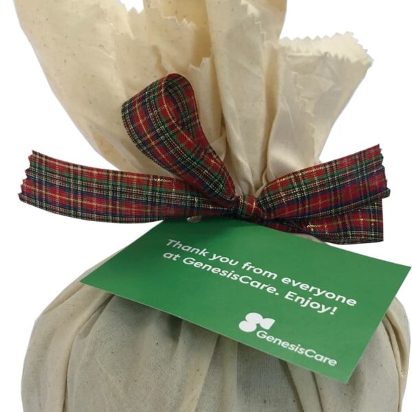 Cloth-wrapped gift with tartan ribbon and green GenesisCare thank you tag attached.