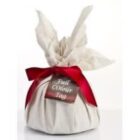 Wrapped gift with a red ribbon and a tag, covered in white cloth with tied corners on top.