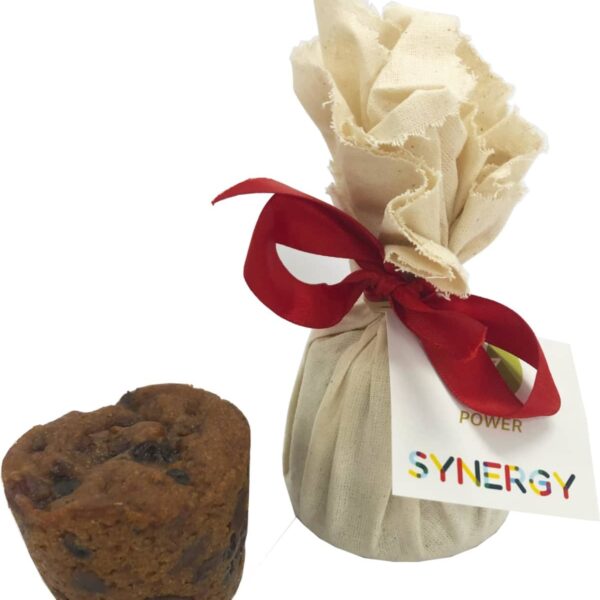 Small brown muffin beside a wrapped cloth package with a red ribbon and a SYNERGY tag.