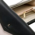 Close-up of a black and beige leather purse with a gold zipper and button.