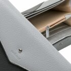 Close-up of an open gray leather wallet showing compartments and a zipper pocket.