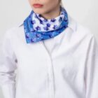 Woman in white shirt wearing a blue floral scarf around her neck.
