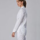 Woman in white medical scrubs standing sideways against a plain light gray background.