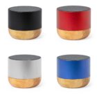 Four small cylindrical speakers with wooden bases in black, red, silver, and blue colors.
