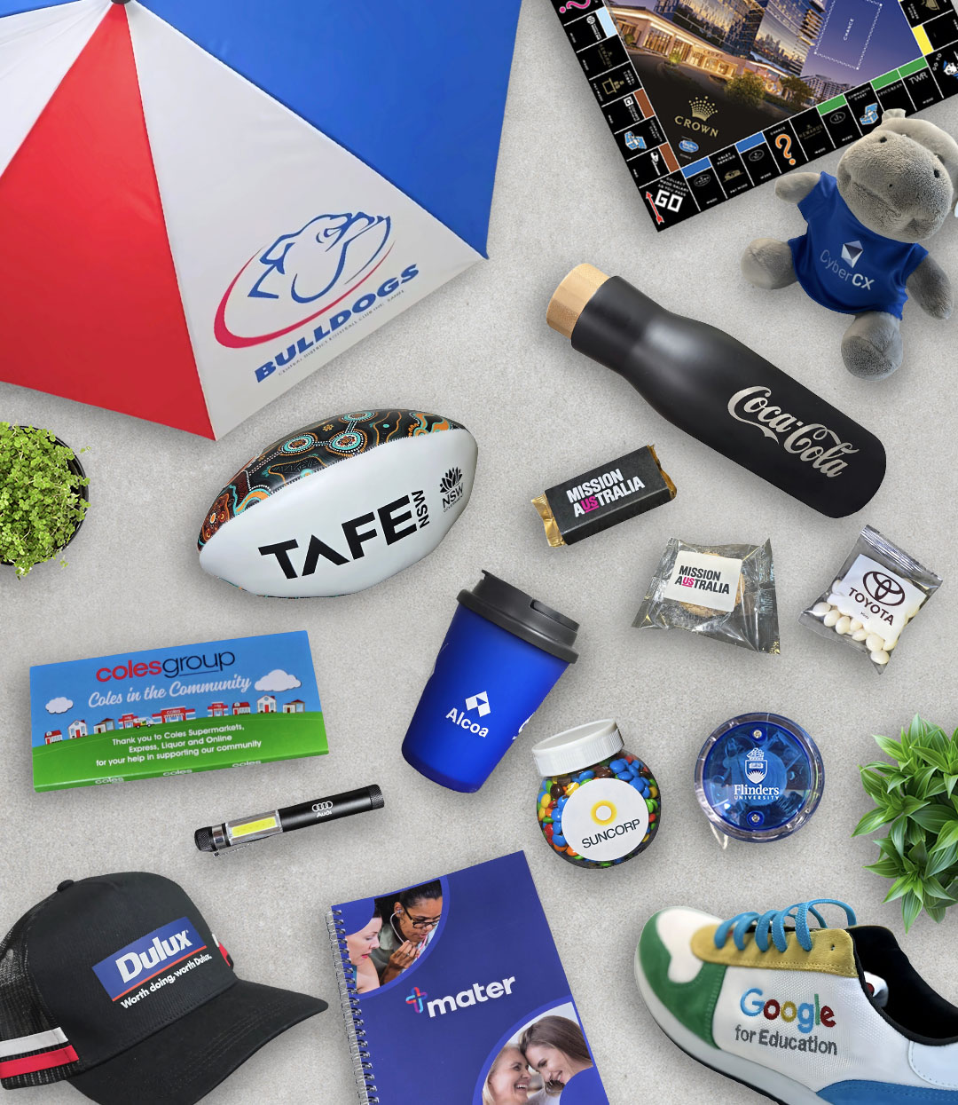 Assorted branded promotional products, including an umbrella, bottles, notebooks, and souvenirs.