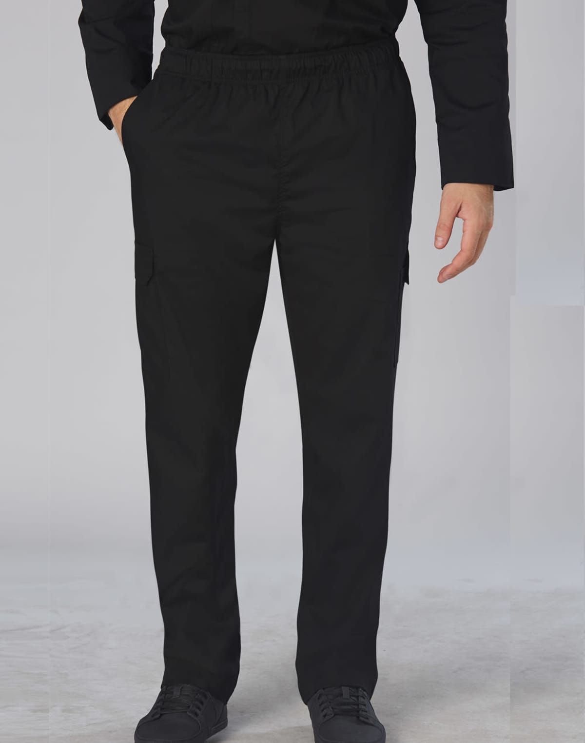 Person wearing black cargo pants and black shoes, with one hand in their pocket.