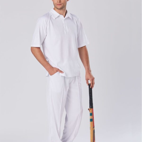 Man in white cricket uniform holding a cricket bat, standing against a plain background.