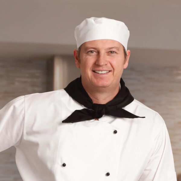 Smiling chef in white uniform and hat with a black neckerchief.
