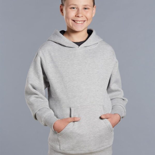 Smiling boy in a light gray hoodie with hands in the front pocket, standing against a gray background.