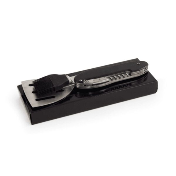 Folded multi-tool grilling utensil with black handle on a black box.