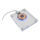 A transparent wireless charging pad with a visible copper coil and connected cable.