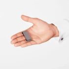 A hand holding a small USB flash drive against a white background.