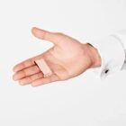 A hand holds a small pink rectangular object against a white background.