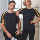 Two people wearing matching black and yellow athletic shirts, posing indoors by a window.