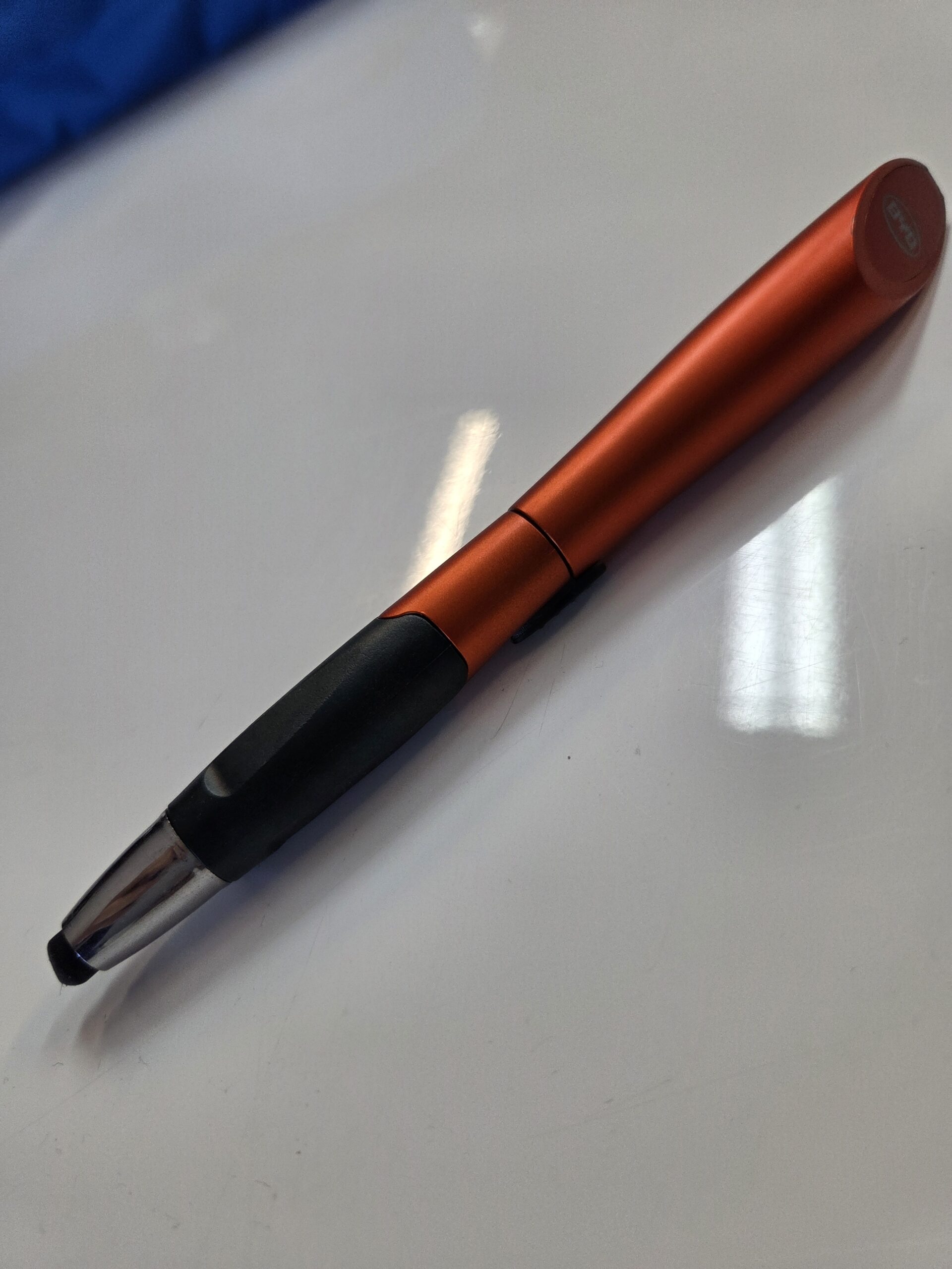 orange and black pen with silver tip on a glossy white surface