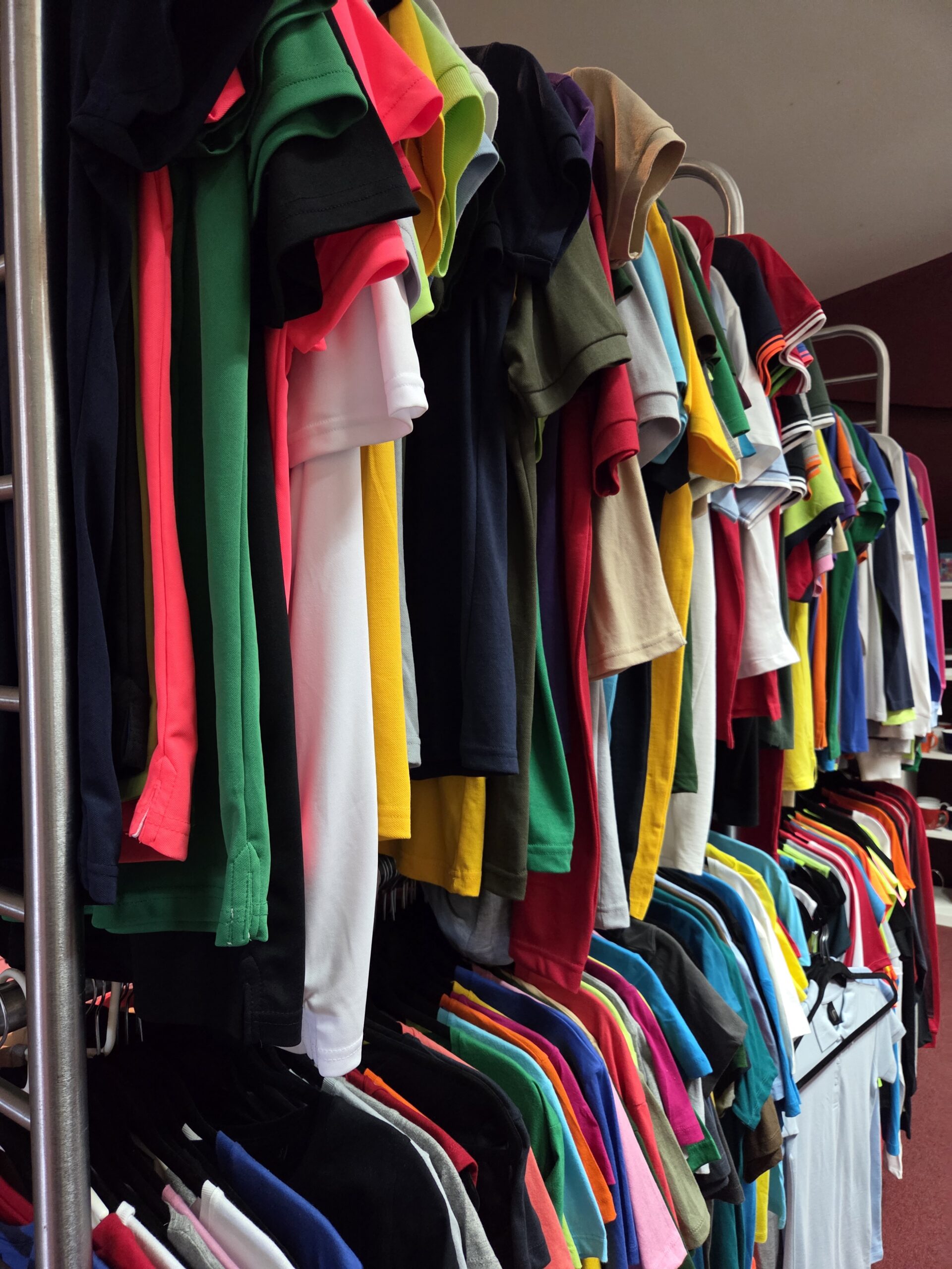 higher view of a photo of variety of shirts displayed in different colors hanging 