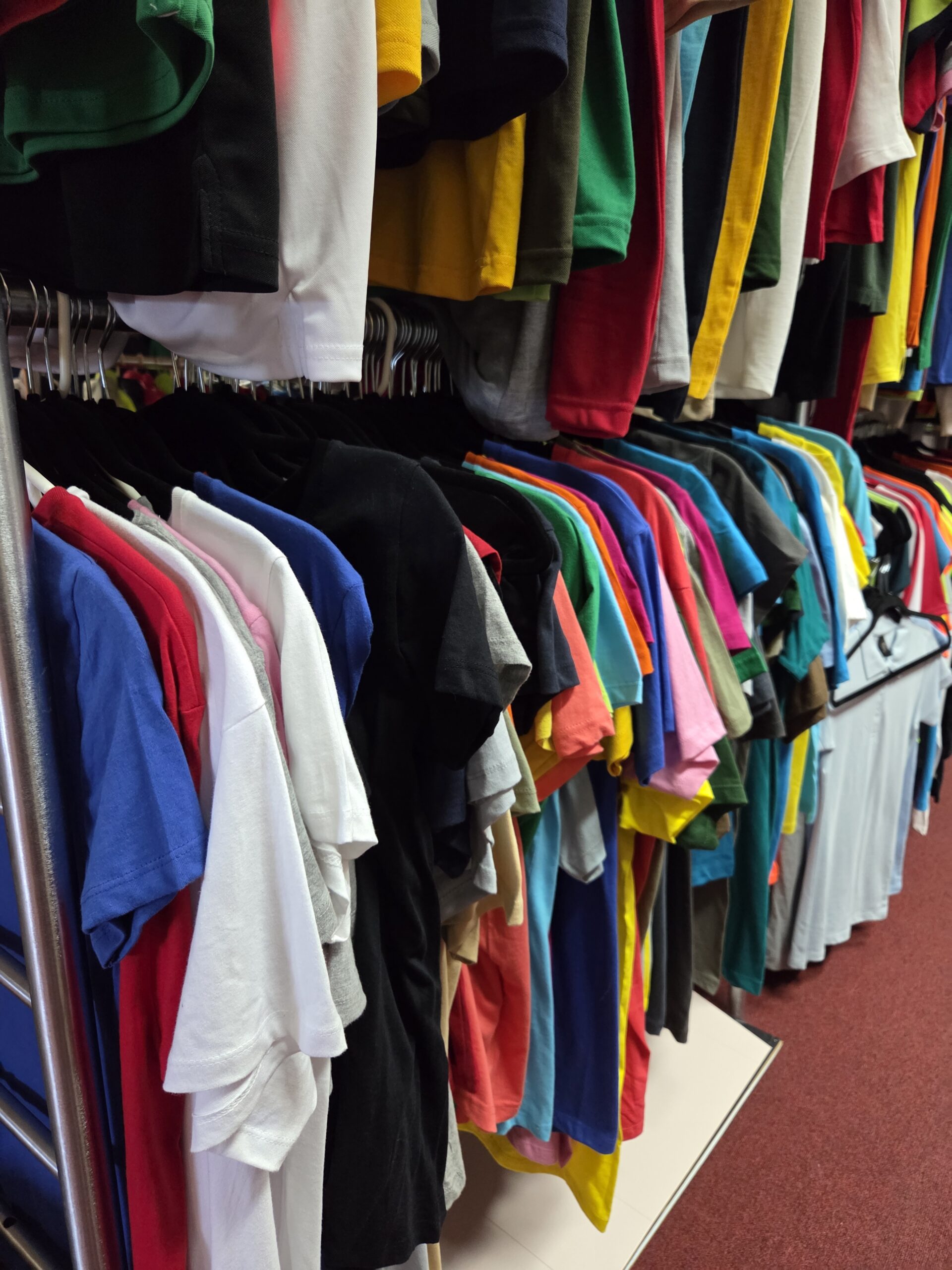 a photo of variety of shirts displayed in different colors hanging 