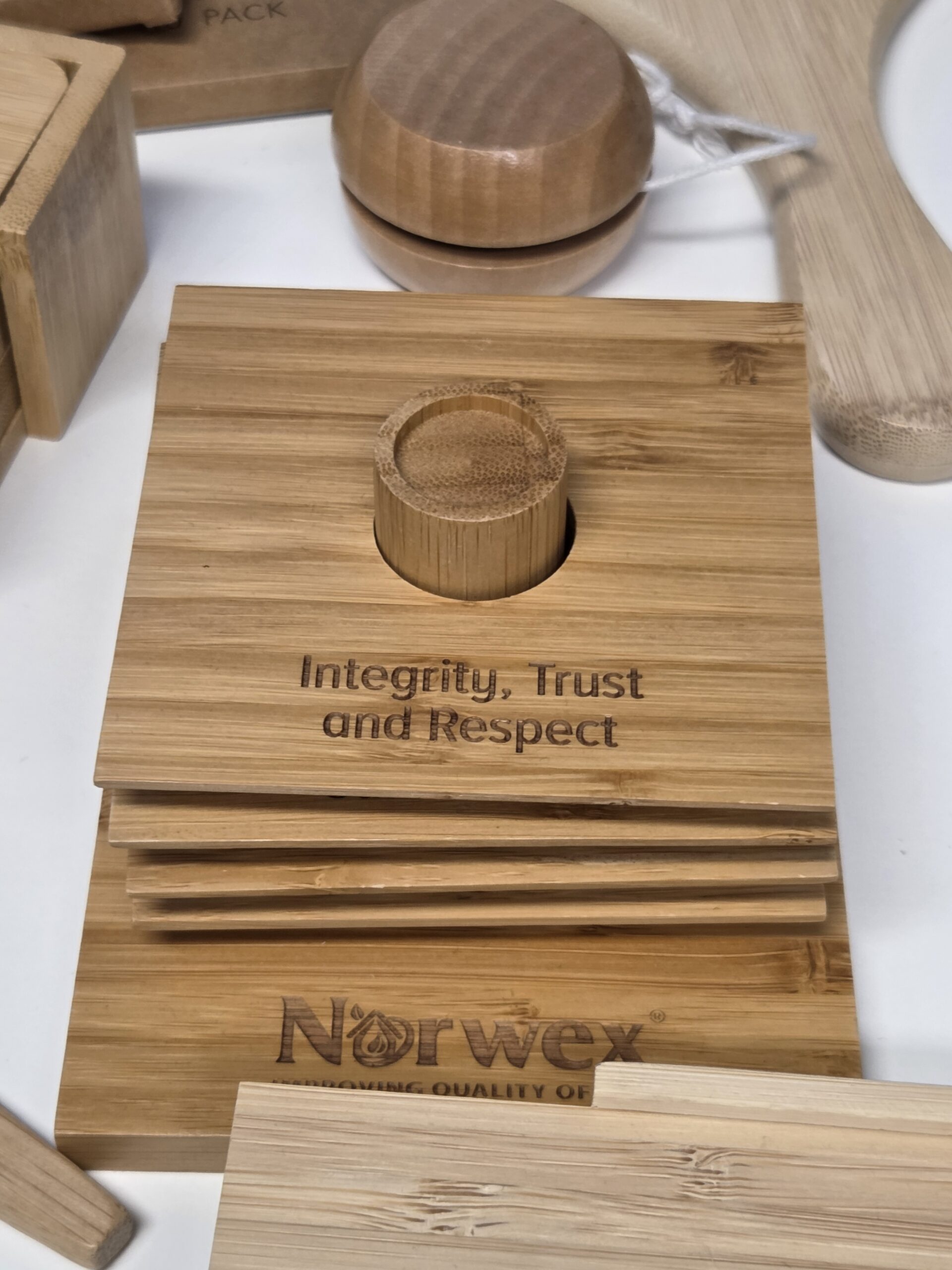 Stacked bamboo coasters engraved with Integrity, Trust, and Respect on top.