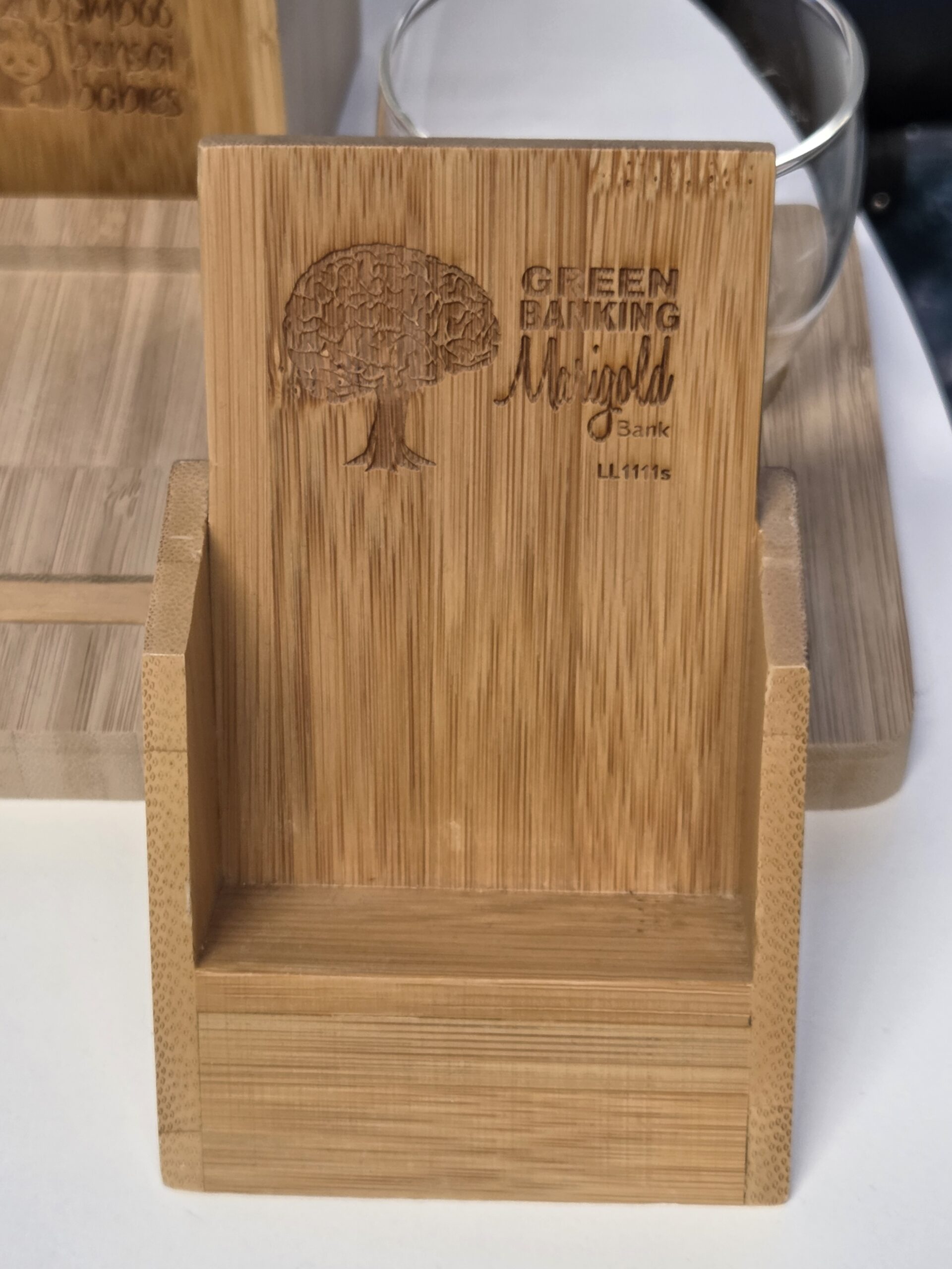 Bamboo phone stand engraved with a tree and text Green Banking, Marigold Bank, L.I. 11%.