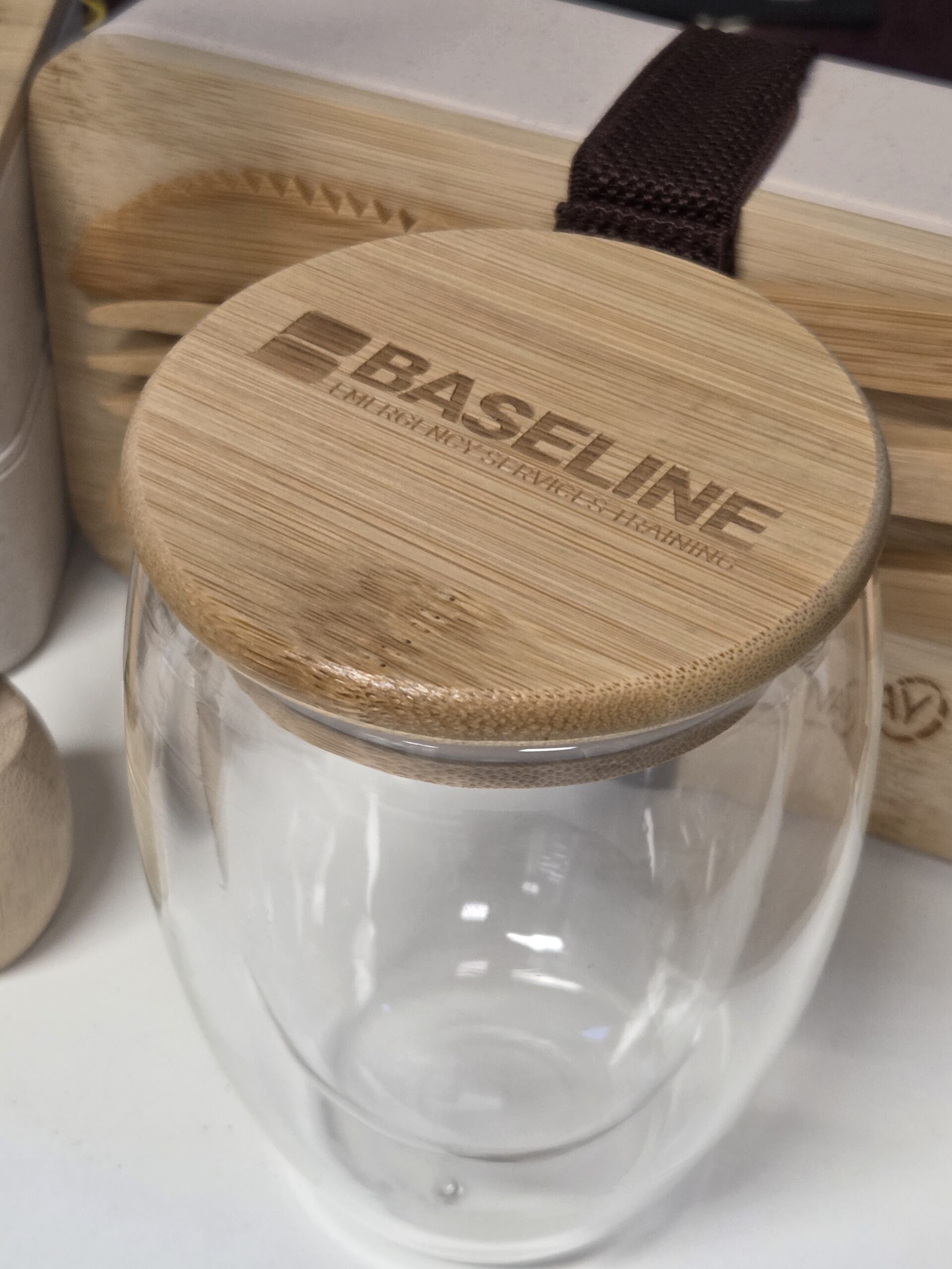A glass cup with a bamboo wooden lid engraved with the word BASELINE.