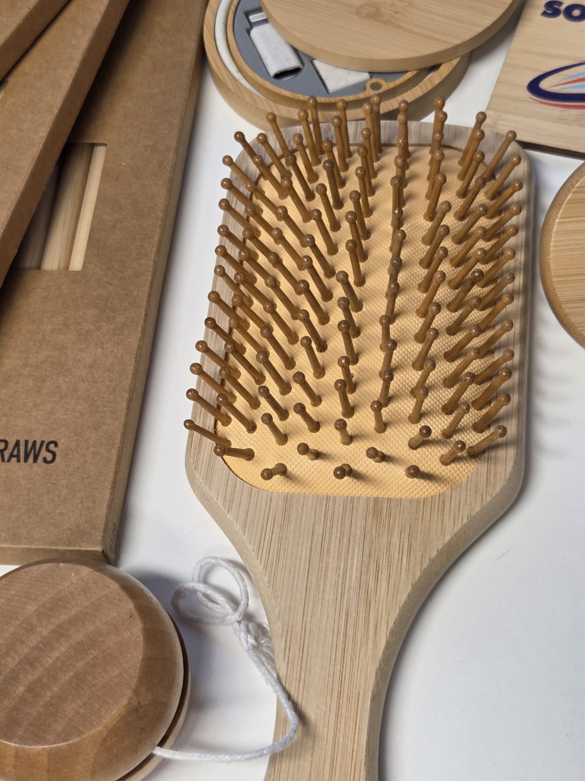 A bamboo hairbrush surrounded by eco-friendly wooden and cardboard items.