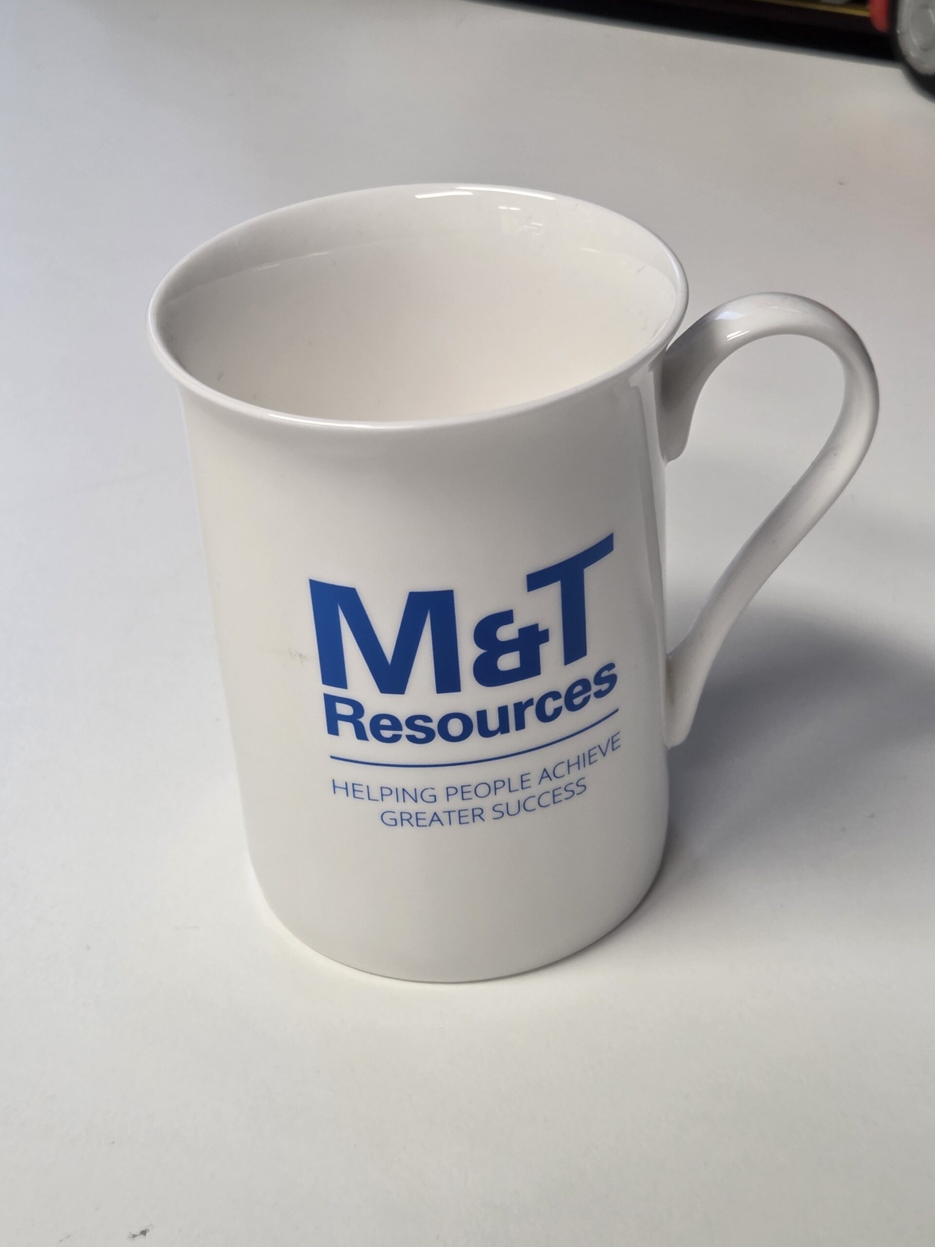 White porcelain mug with M&T Resources and Helping People Achieve Greater Success in blue.