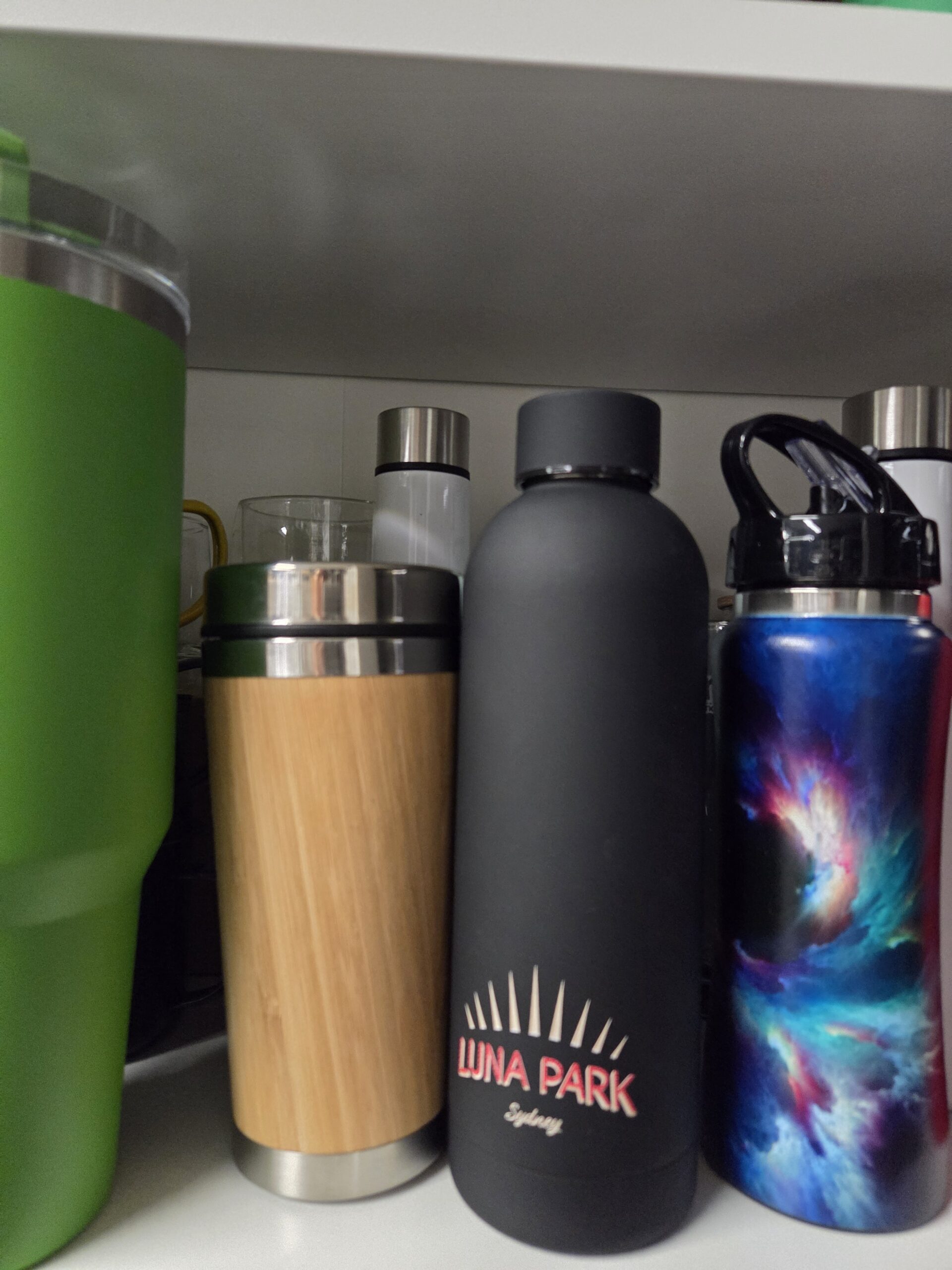 Colorful merch: Four reusable water bottles in bold designs displayed on a shelf.
