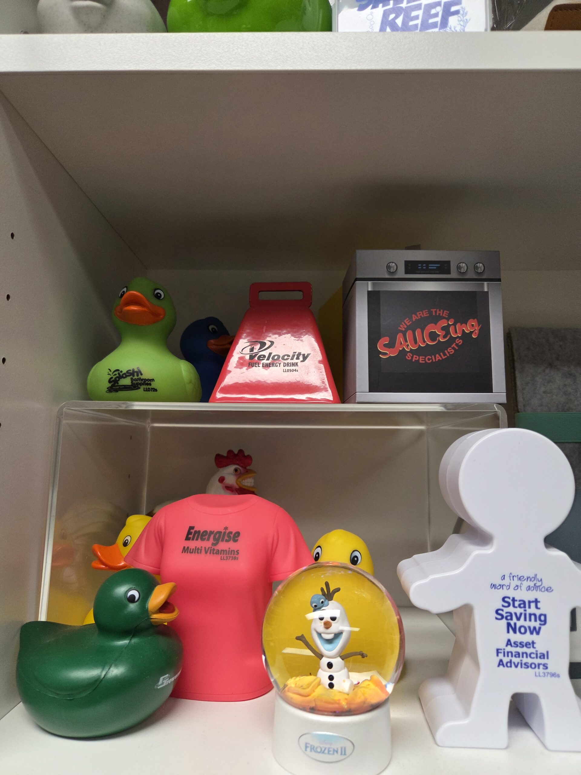 Shelf with rubber ducks, a snow globe, a cowbell, and various marketing merch displayed.