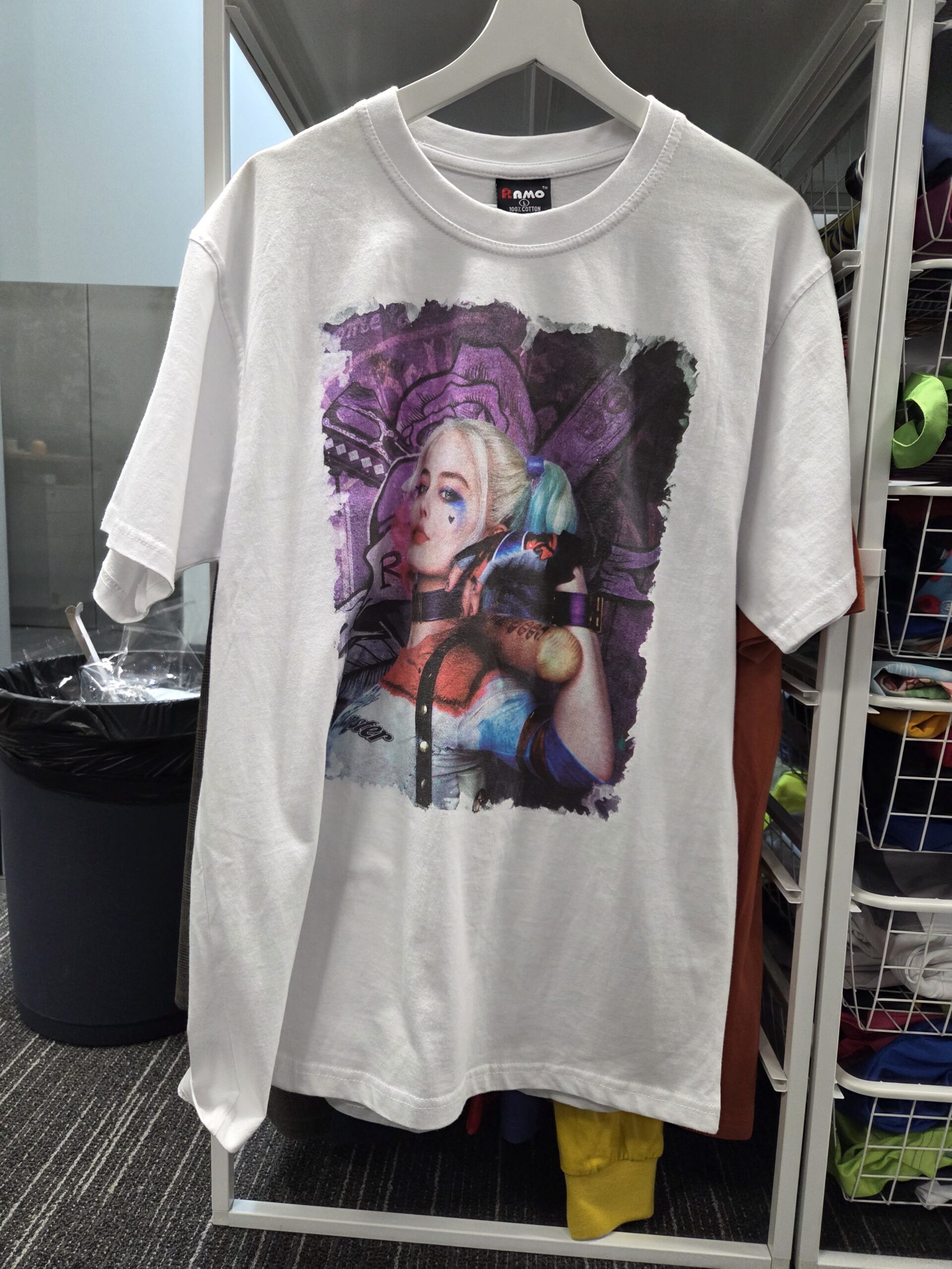 White t-shirt with a colorful anime-style print made using digital printing, hanging on a rack.