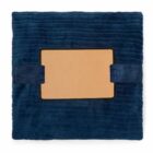 A blue textured pillow with a tan rectangular panel in the center and two fabric straps.