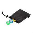 Three colorful rings partially out of a small black drawstring bag on a white background.