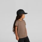 Young child in a brown t-shirt and black cap standing sideways against a plain background.