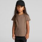 Child with long hair wearing a brown t-shirt and black cap stands against a plain background.