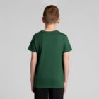A boy wearing a green t-shirt and black shorts stands facing away from the camera.