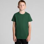 Boy in a plain green t-shirt and black pants standing against a gray background.