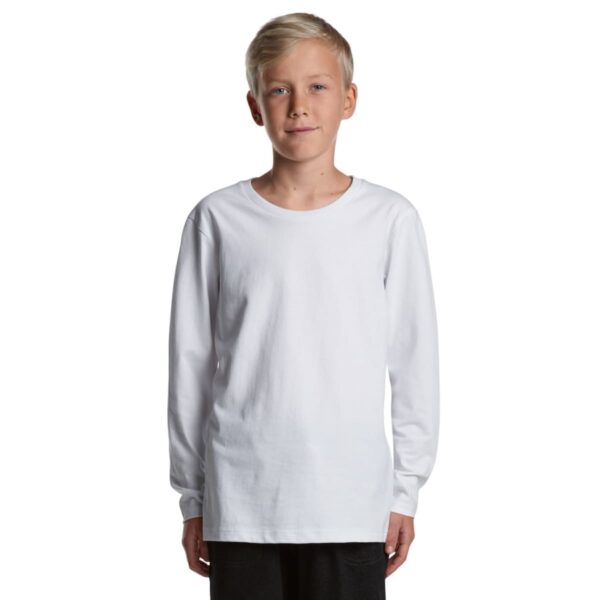 Boy with blond hair wearing a plain white long-sleeve shirt and black pants, facing forward.