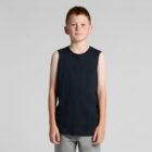 A boy in a black sleeveless shirt and gray pants stands against a plain background.
